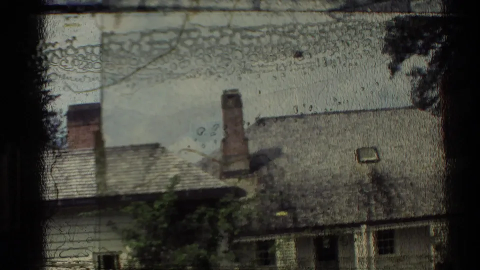 1981 New Zealand home-movie frame with a partially obscured building exterior, roofline, chimneys, and heavy film-edge marks.