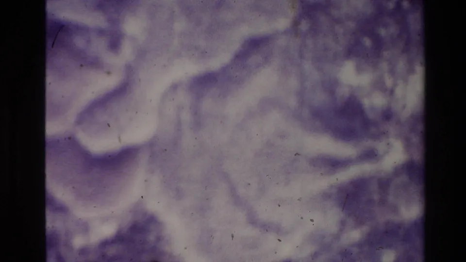 Purple-tinted 8mm texture frame with soft focus, specks, and uneven exposure, preceding the house exterior shot.