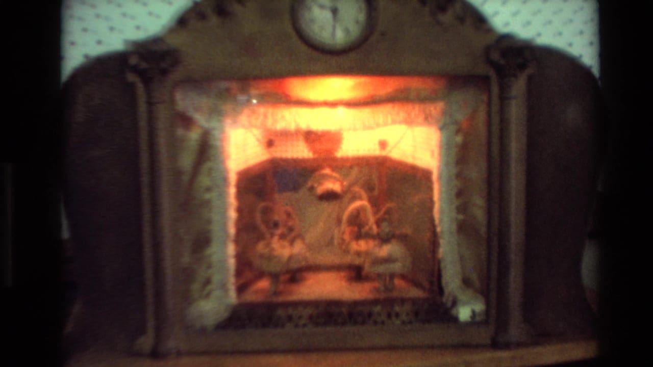 Close view of a lit mantel-style decoration with small figures behind a glowing front panel.