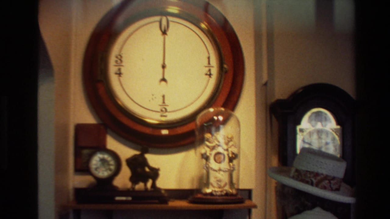 Large round wall clock above a shelf with smaller clocks and glass-domed objects.