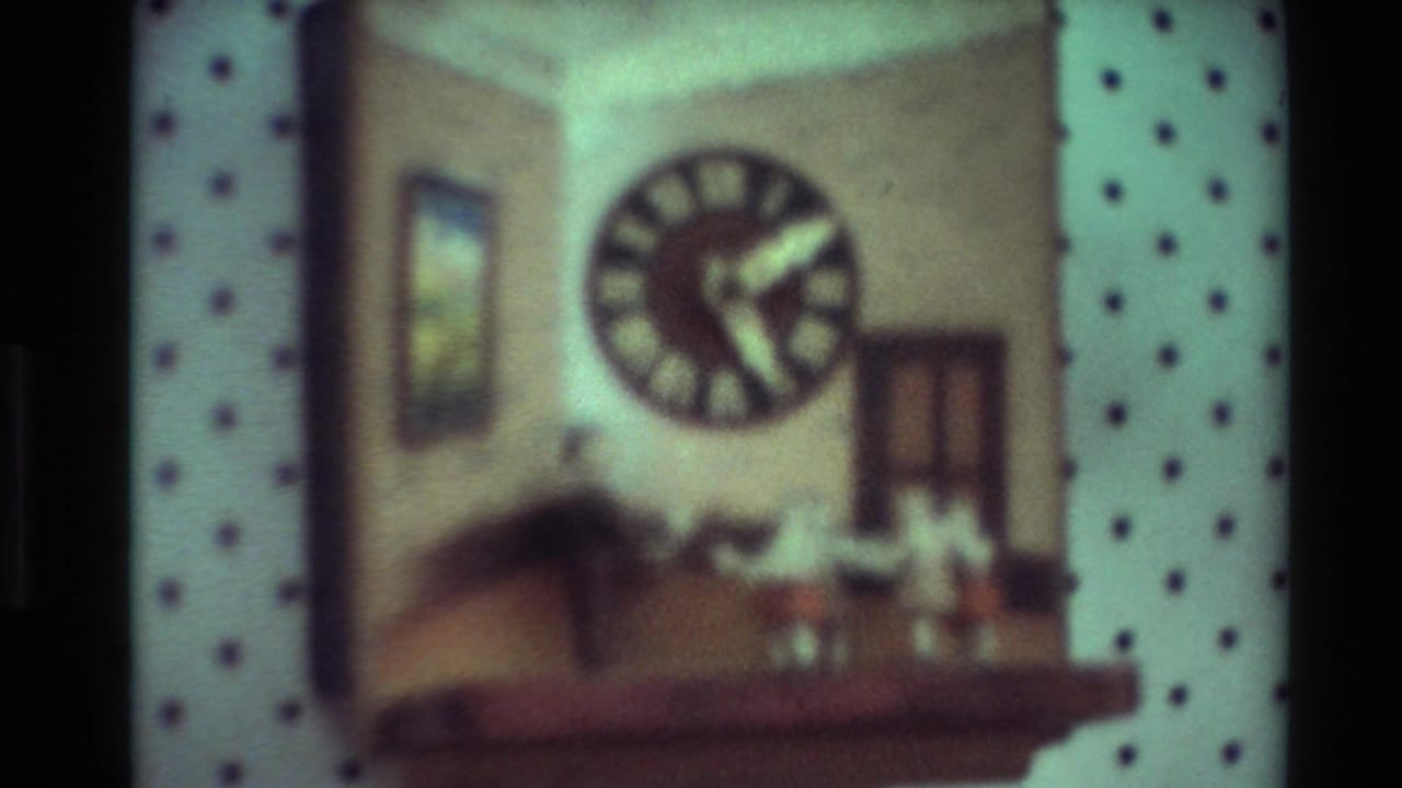 Soft 8mm view of a shelf display with a large round clock face and small decorative objects in the supplied New Zealand 1981 clip.