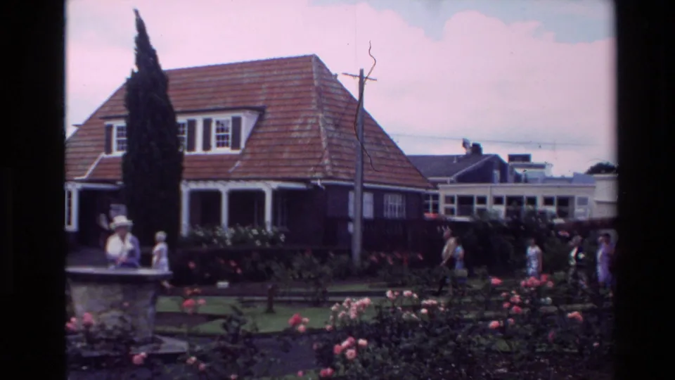 1981 New Zealand 8mm frame showing a red-tiled house, rose garden, lawn, fountain, and visitors on the grounds.