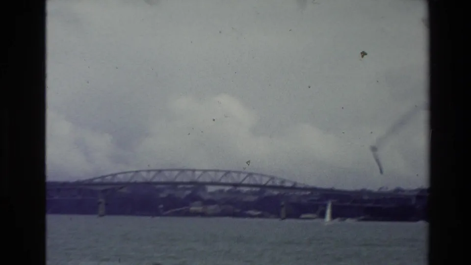 1981 New Zealand 8mm view of a truss bridge over water with a small white sailboat in the foreground.