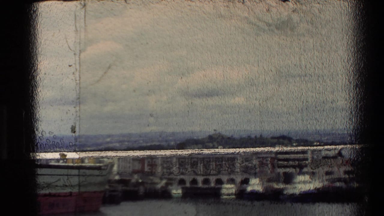 Distant waterfront view with buildings, harbor water, and a dark vertical film edge.