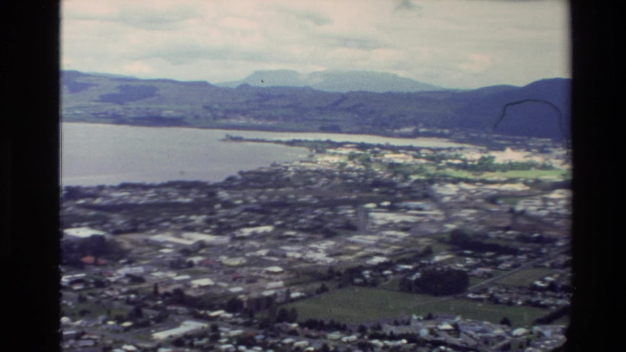 Elevated view of a coastal town beside a bay and hills.