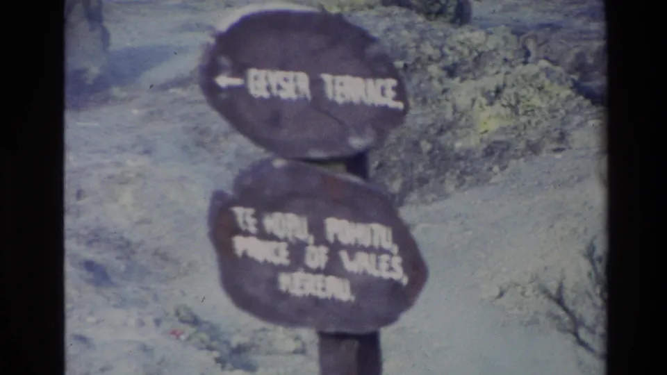 1981 New Zealand 8mm frame showing a weathered wooden sign with white lettering against rocky ground and sparse vegetation.