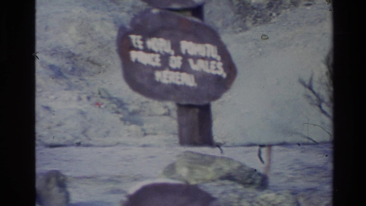 Close view of a wooden sign with partially legible white lettering.