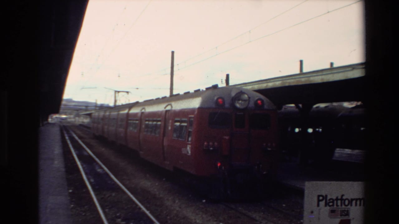 Red and silver passenger train at a New Zealand station platform in 1981, with a Platform 4 sign partly visible.