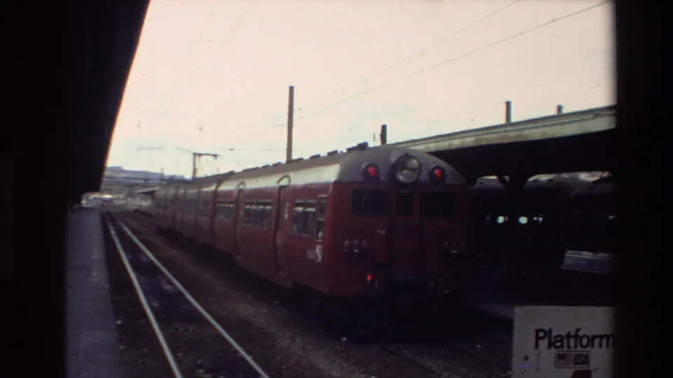 Red and silver passenger train at a New Zealand station platform in 1981, with a Platform 4 sign partly visible.