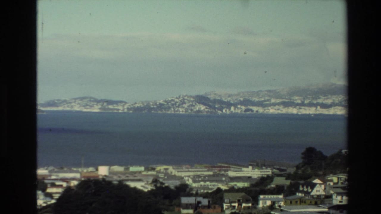 Elevated view across a bay toward a distant mountain range with waterfront buildings below.
