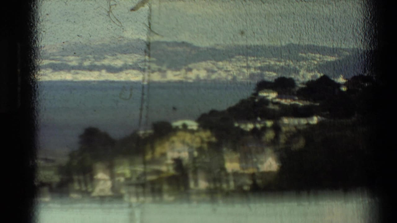 Soft coastal view through dark frame edges, with water, shoreline, and hills.
