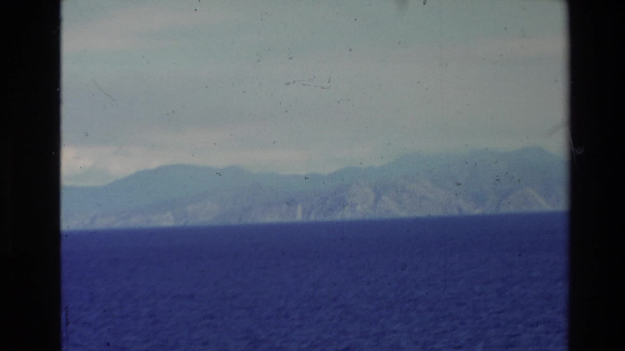 Hazy mountainous coastline beyond a wide band of deep blue water.