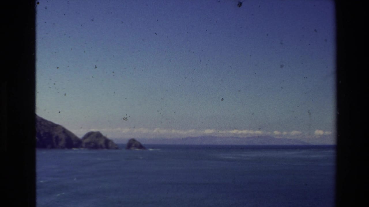 Open blue sea with distant rocky islands under a clear sky.