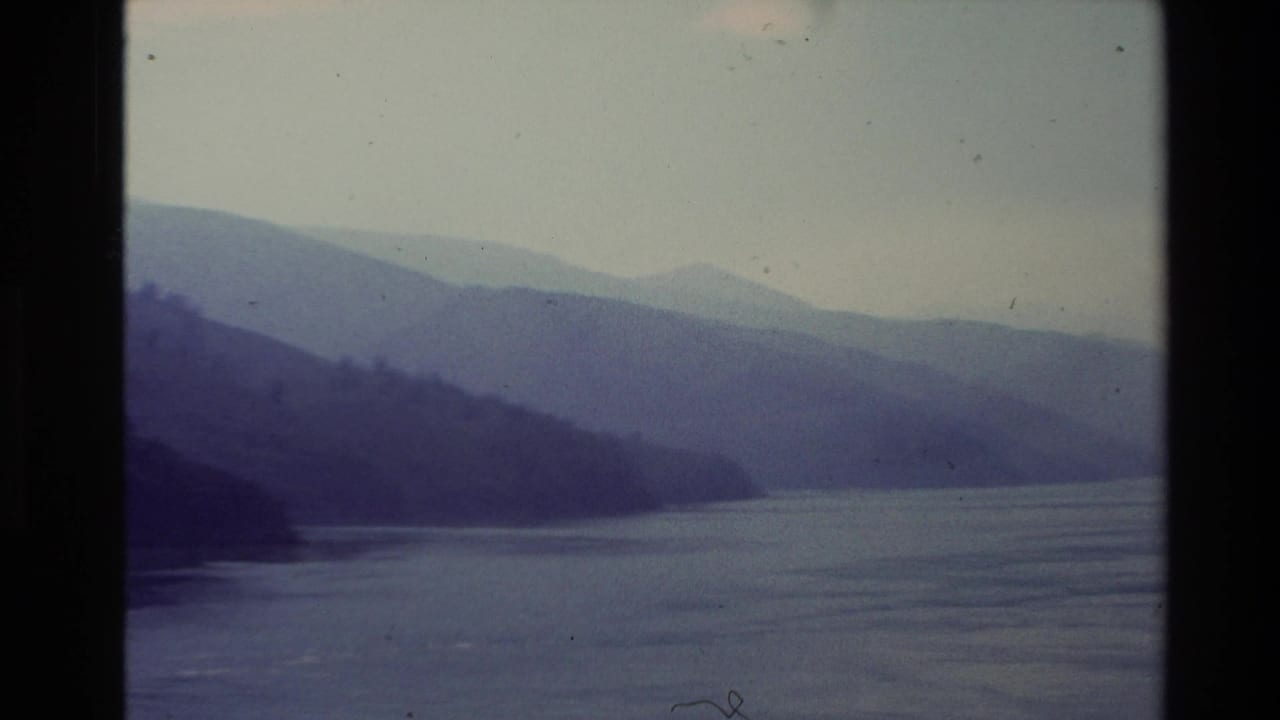 Dark headland and distant blue mountains beside a broad lake.