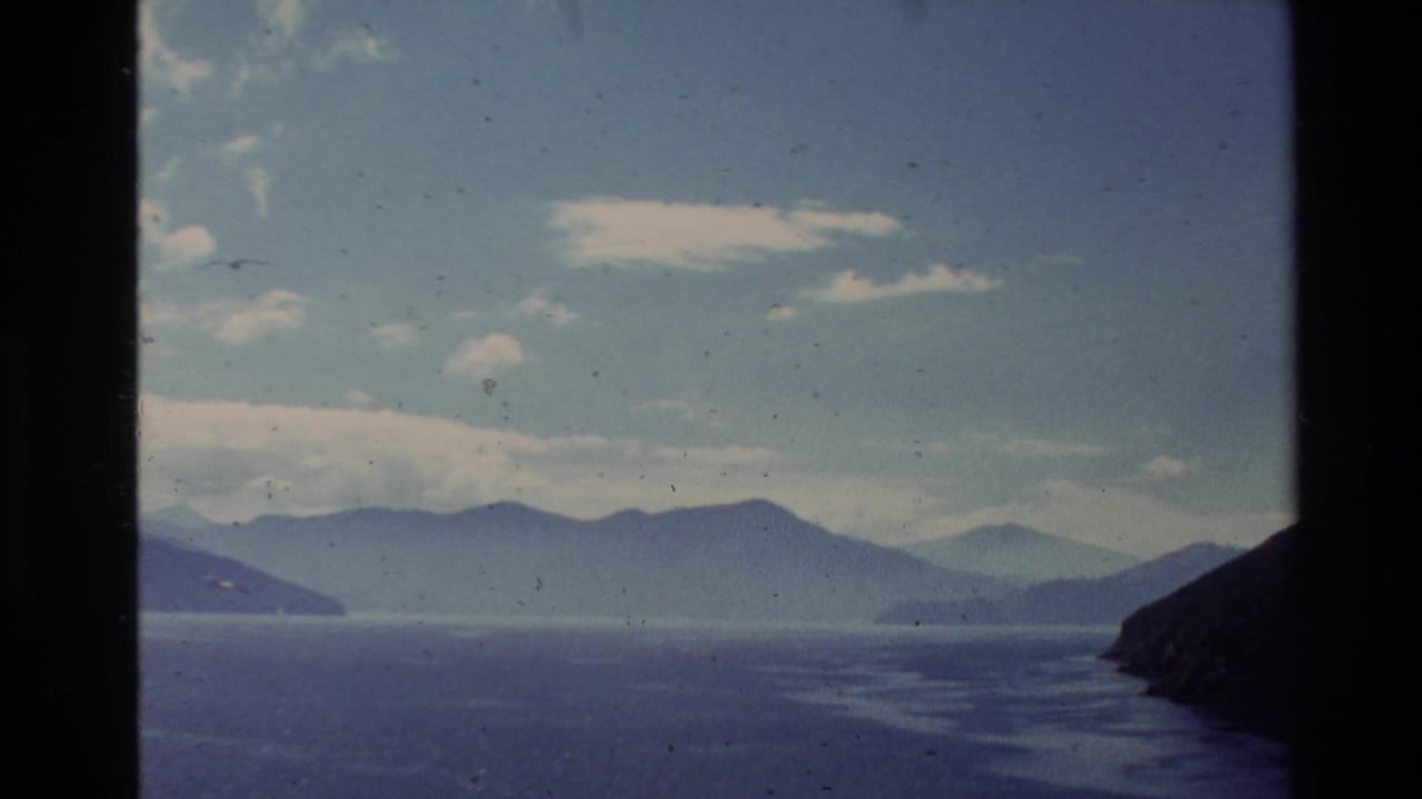 Wide lake and layered hills beneath a partly cloudy sky.