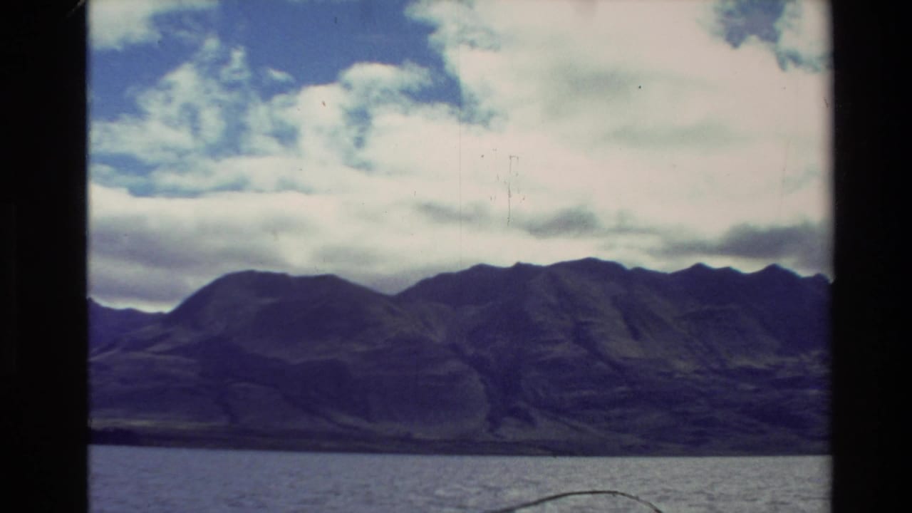 Mountain range across a lake beneath a partly cloudy sky.