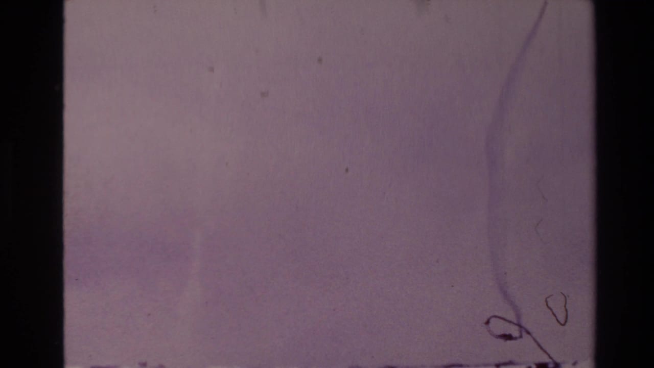 Faded film frame with mostly blank tinted area and visible scratches beside a dark film border.