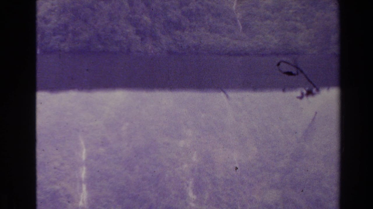 1981 New Zealand 8mm frame with indistinct lake or mountain forms, heavy purple cast, film scratches, and soft exposure.