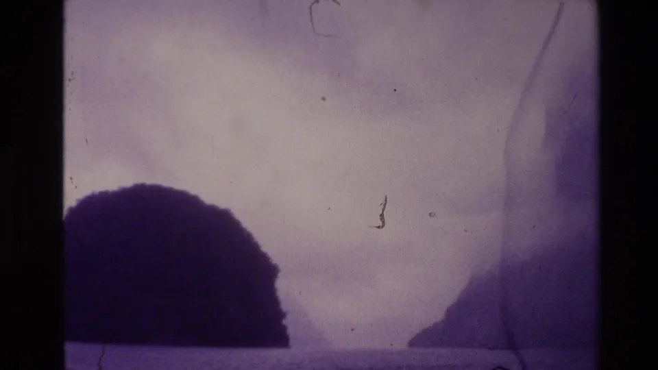 1981 New Zealand 8mm frame showing mist over water and dark rugged hills, with purple tint, grain, and film wear.