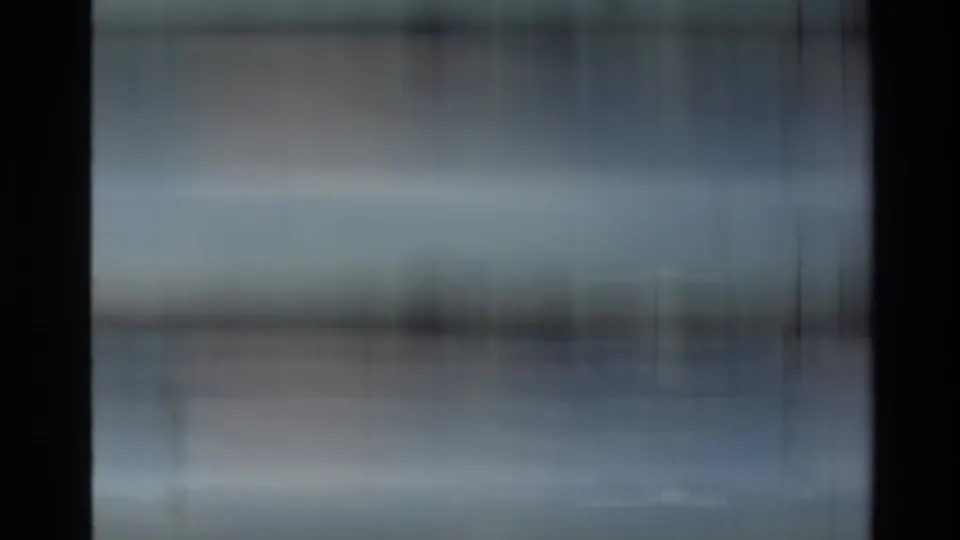 Abstract, heavily blurred 8mm frame likely showing blue-gray water or sky, with vertical film marks and exposure streaking.