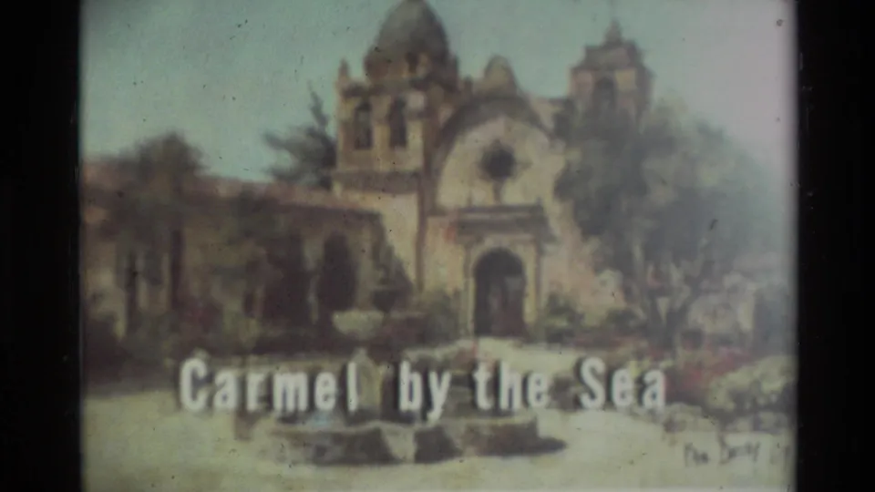 1982 Carmel-by-the-Sea travel frame showing a Spanish-style mission building with arched entrance, dome, trees, and title text.
