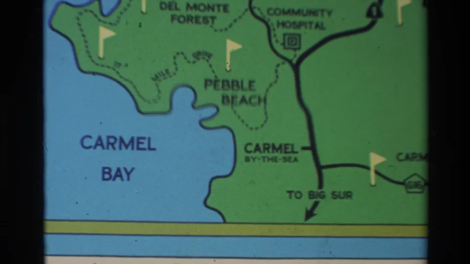 Close 8mm map frame centered on Carmel Bay, Pebble Beach, Carmel-by-the-Sea, and a directional arrow to Big Sur.