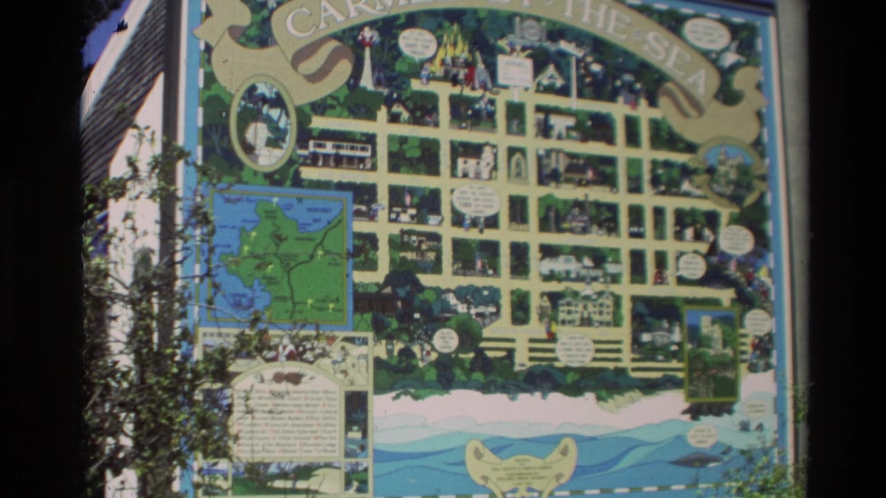 Colorful illustrated Carmel town map mounted outdoors with street grid and small scene panels.