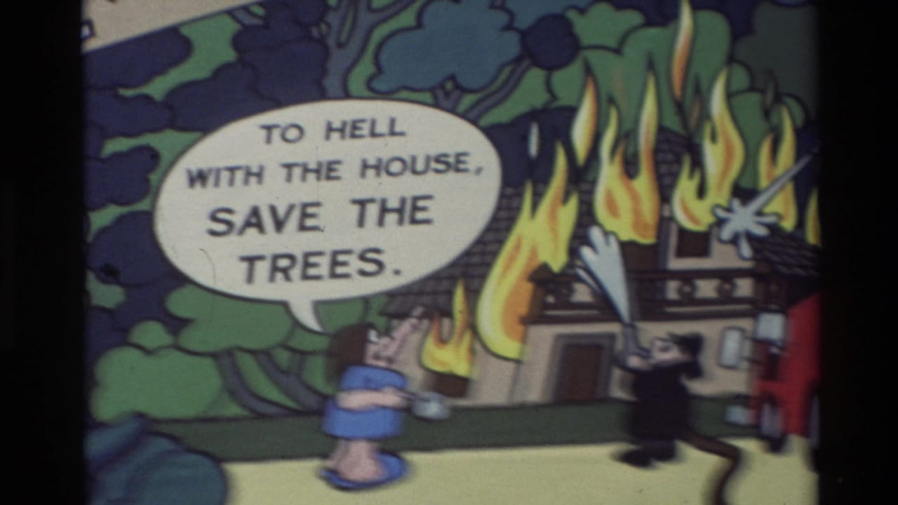 1982 Carmel home-movie frame showing a hand-drawn cartoon house fire with a figure, flames, trees, and a speech bubble reading about saving trees.