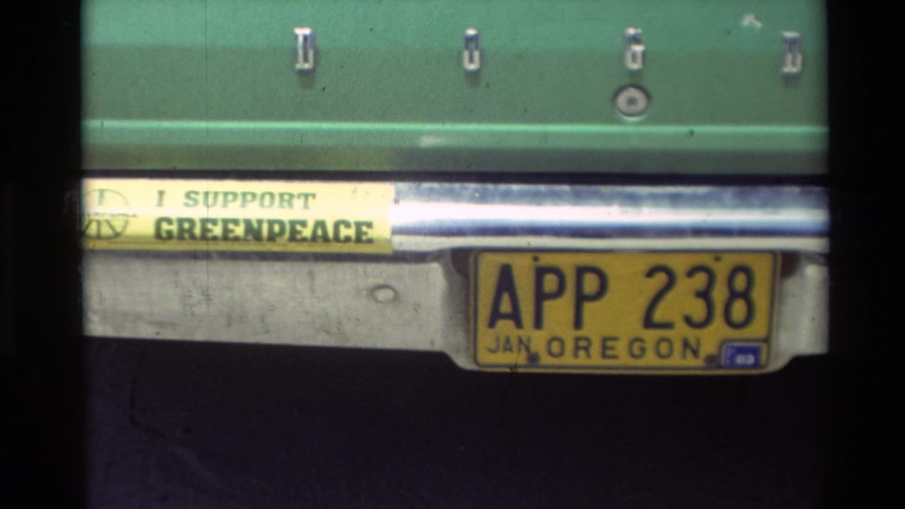 1982 Carmel home-movie frame showing an Oregon plate on a green car beside an I SUPPORT GREENPEACE bumper sticker.