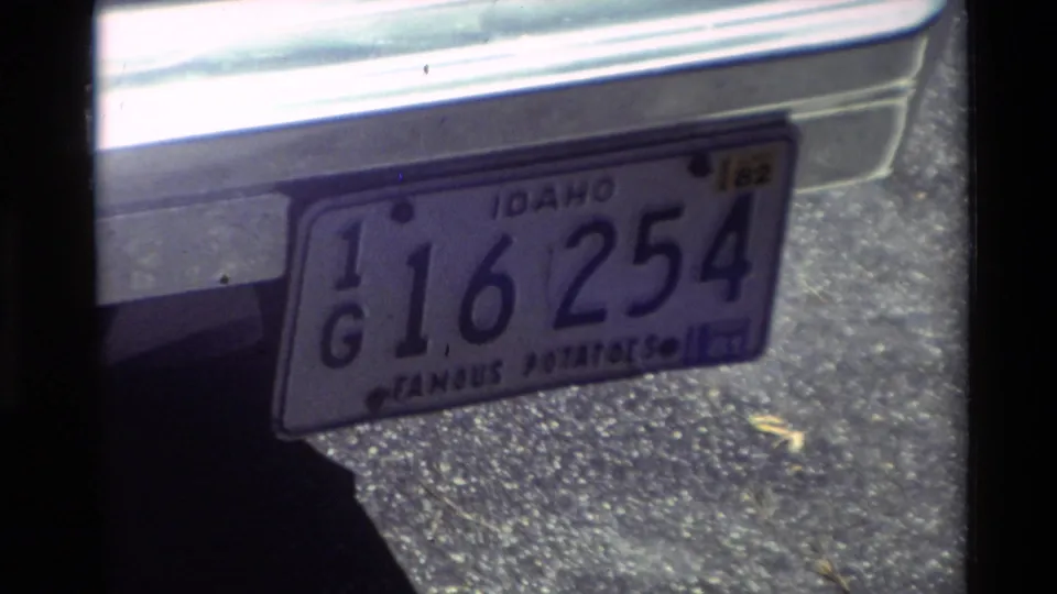 1982 Carmel frame showing an Idaho plate reading 16 254 with Famous Potatoes text on a parked car.