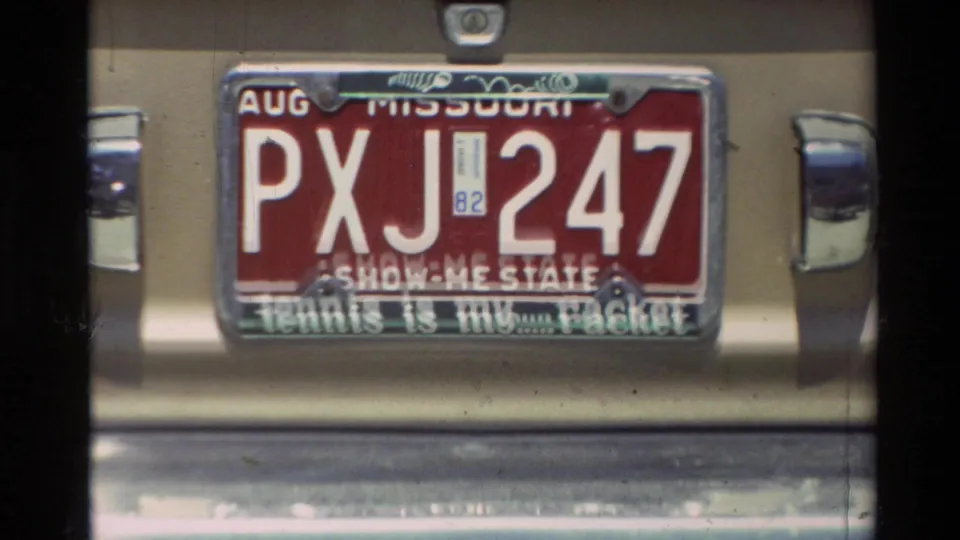 Close Super 8 view of a Missouri plate reading PXJ 247 on a rear bumper in the 1982 Carmel clip.