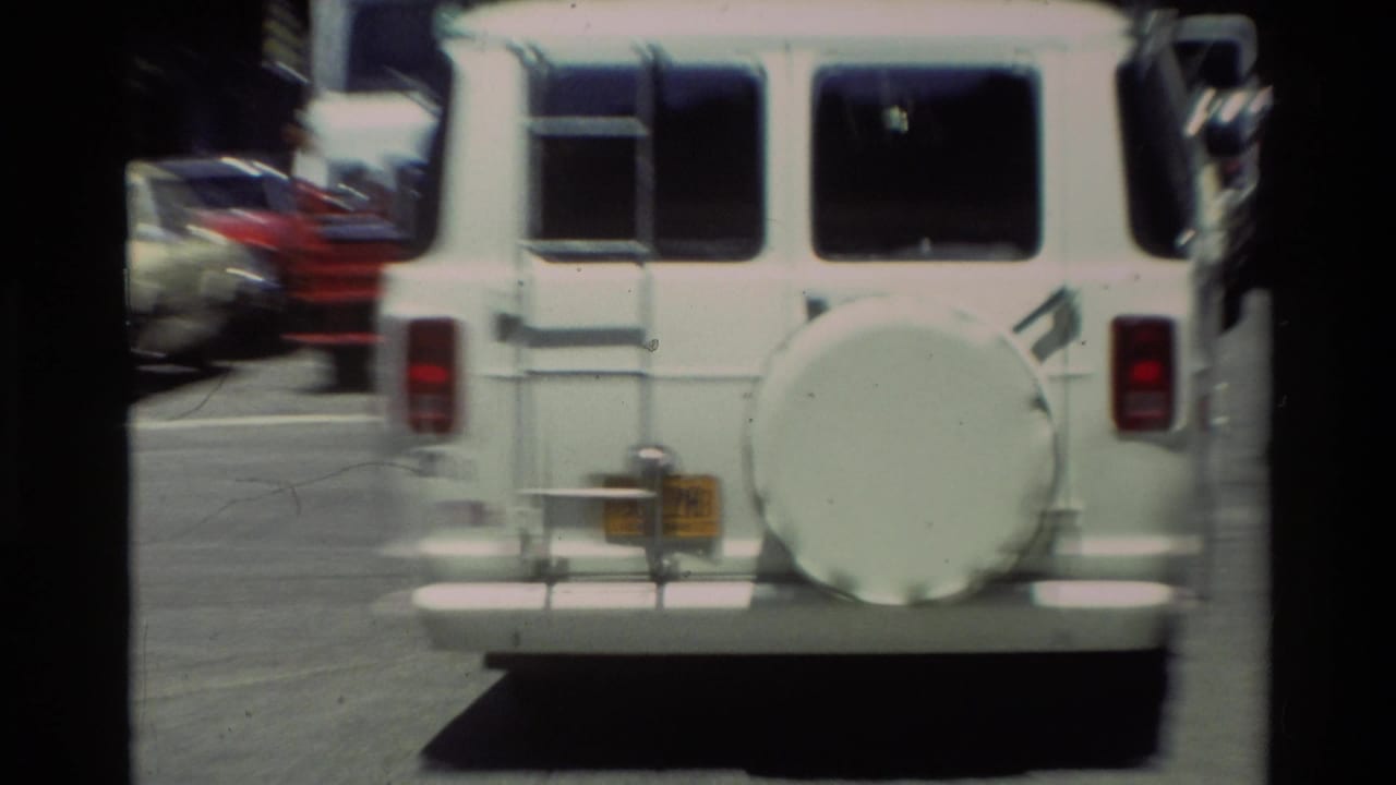 Rear of a white van with a spare tire on a street.