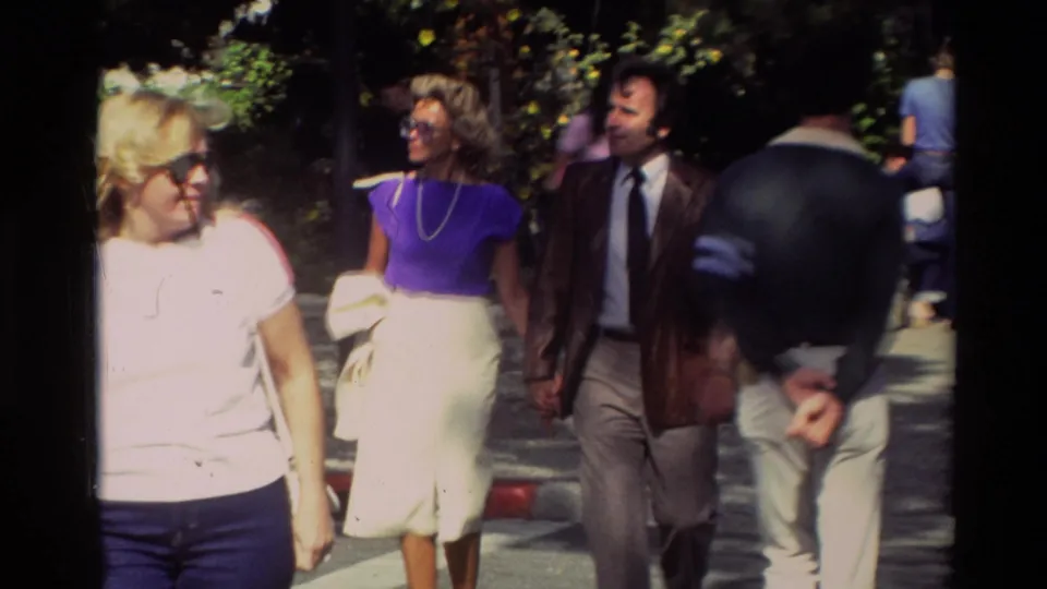 1982 Carmel sidewalk footage showing adults walking and talking in sunglasses, jackets, skirts, and casual streetwear.