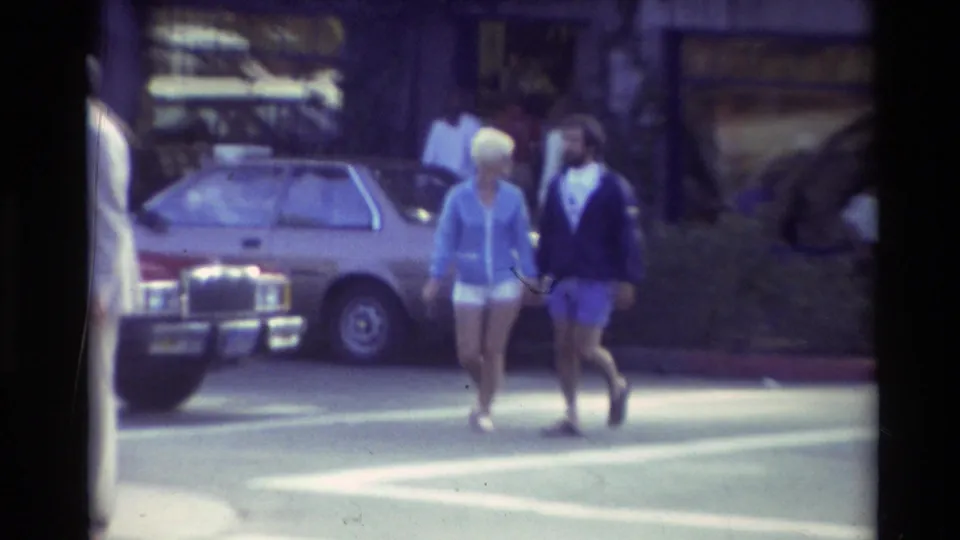 Carmel, California 1982 street crossing with two casually dressed pedestrians passing in front of a parked car.