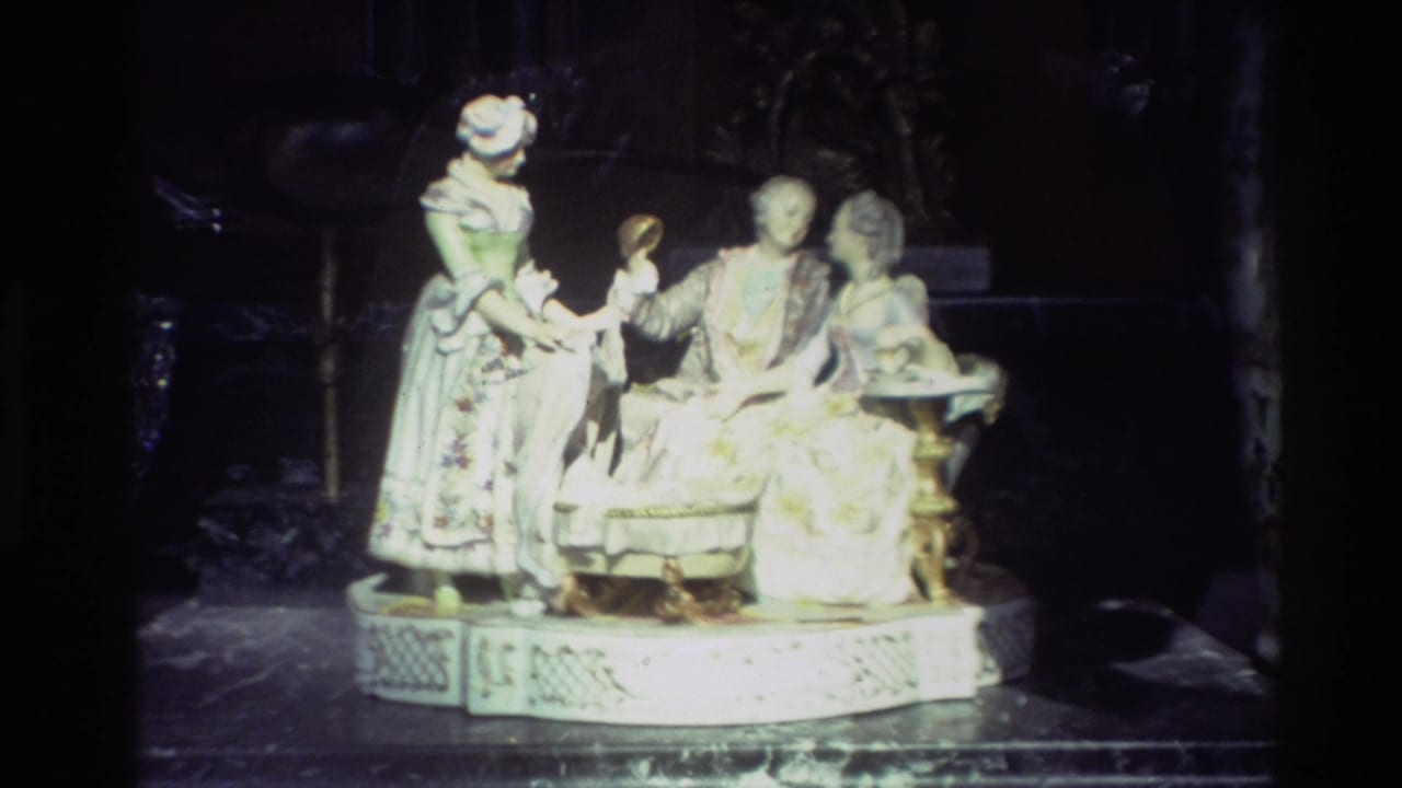 Porcelain figurine group on a dark display surface inside a dim shop window.