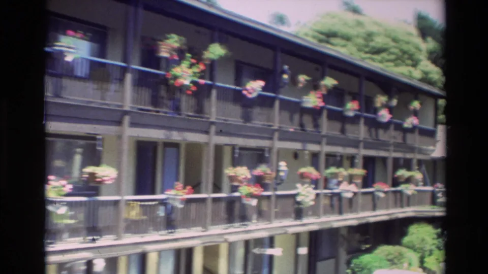 Carmel apartment building facade in 1982, showing repeated balcony railings, doors, windows, and hanging flowers.