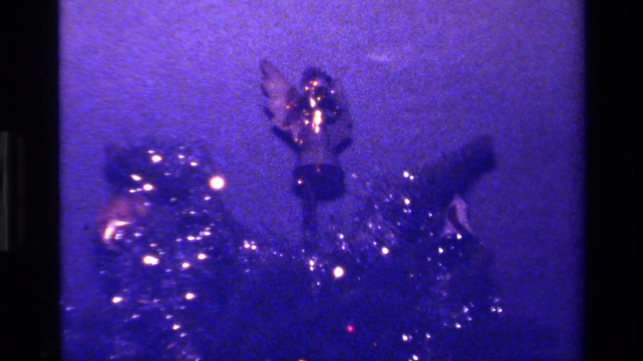 1979 California 8mm frame showing a purple-tinted Christmas tree close-up with tinsel, lights, and a small shiny ornament.