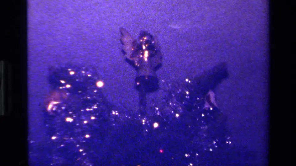 1979 California 8mm frame showing a purple-tinted Christmas tree close-up with tinsel, lights, and a small shiny ornament.