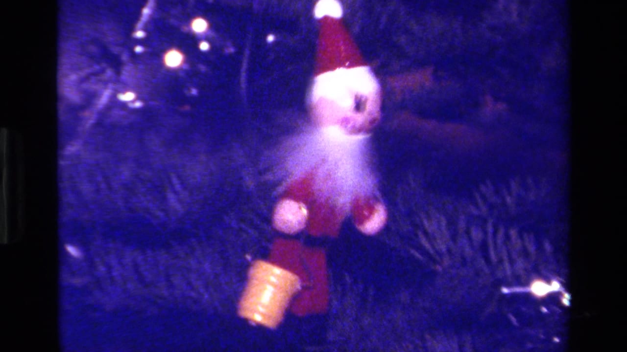 1979 California 8mm frame showing a small Santa ornament on pine branches with holiday lights and a blue color cast.