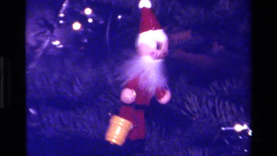 1979 California 8mm frame showing a small Santa ornament on pine branches with holiday lights and a blue color cast.