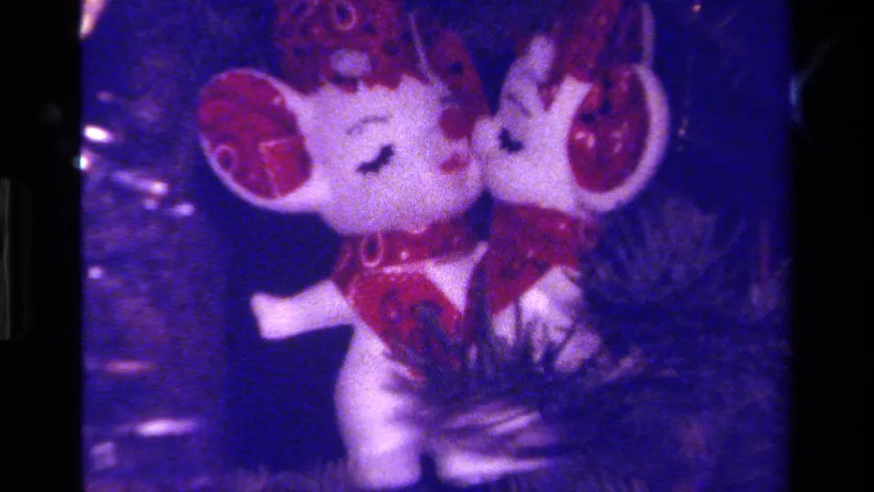 Close-up of two mouse figurines appearing to kiss on a Christmas tree, filmed in grainy 1979 California 8mm footage.