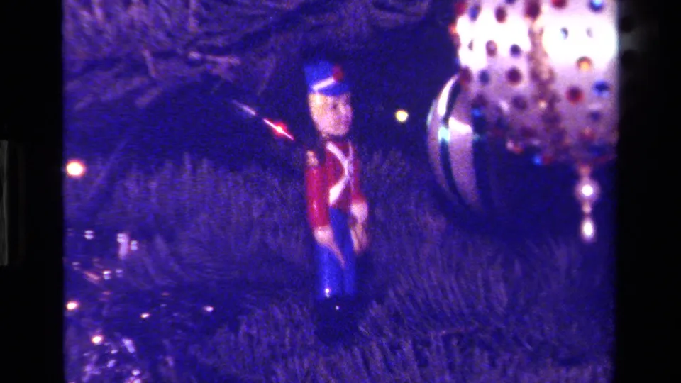 1979 California home-movie frame with a toy soldier ornament beside a reflective dotted bauble and tree lights.