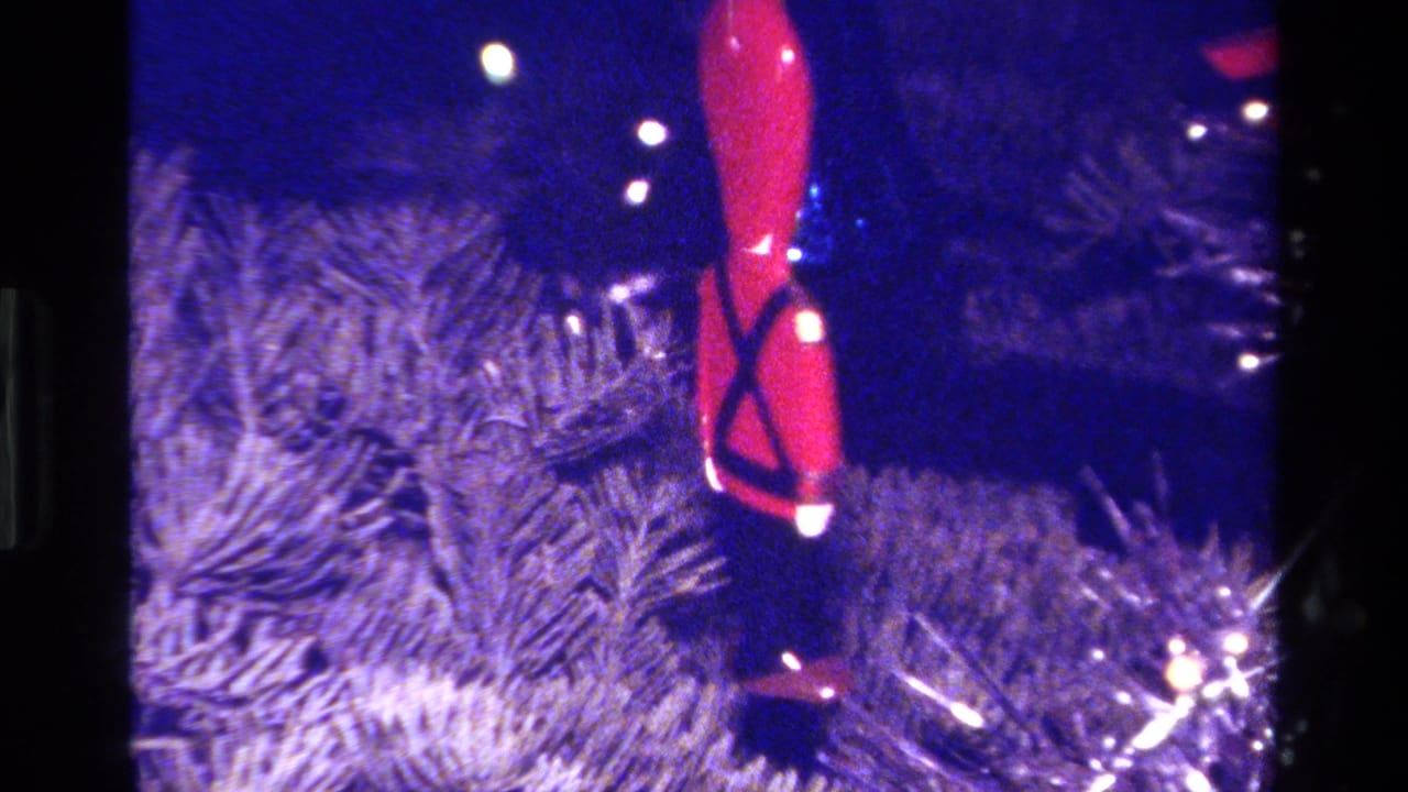 Small red soldier ornament hanging on a Christmas tree, seen in blue-tinted 1979 California 8mm footage.