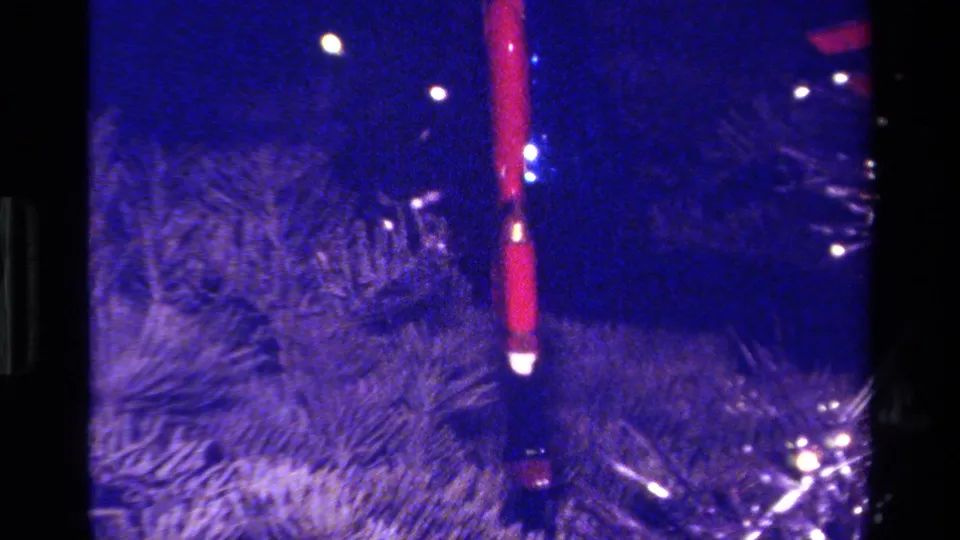 Close 8mm view of a red soldier ornament on a Christmas tree, with soft focus and blue color shift.