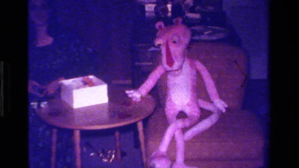 The pink stuffed animal sits upright on a chair next to a small table and white gift box in the 1979 holiday home interior.