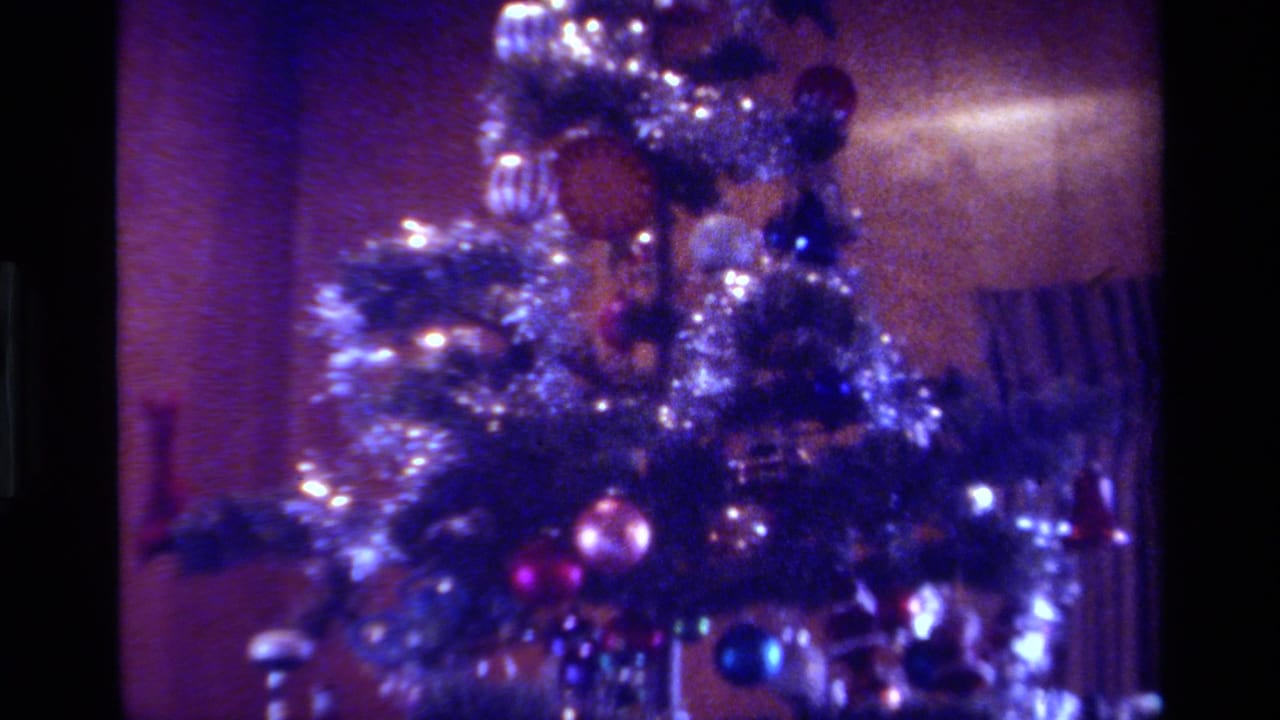 1979 California home-movie frame showing a Christmas tree with silver tinsel, colorful ornaments, and purple-blue film color shift.
