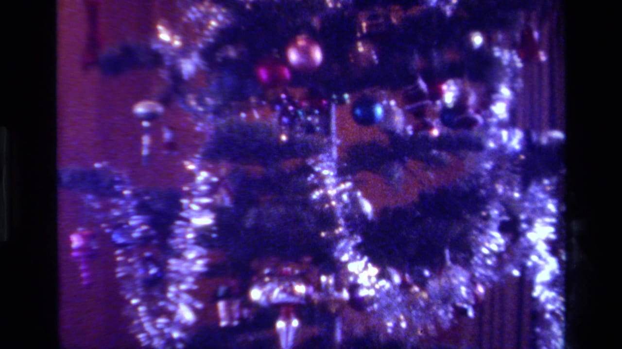 1979 California 8mm frame showing the lower decorated tree area with dense tinsel, colored lights, and soft purple-blue exposure.
