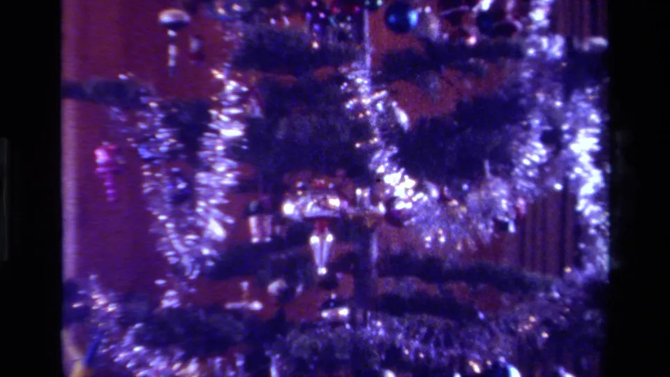 1979 California home-movie close-up of a Christmas tree with heavy silver tinsel, colored ornaments, and visible 8mm grain.