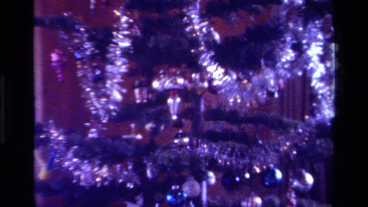 Close view of a Christmas tree with silver tinsel, ornaments, and soft colored lights.