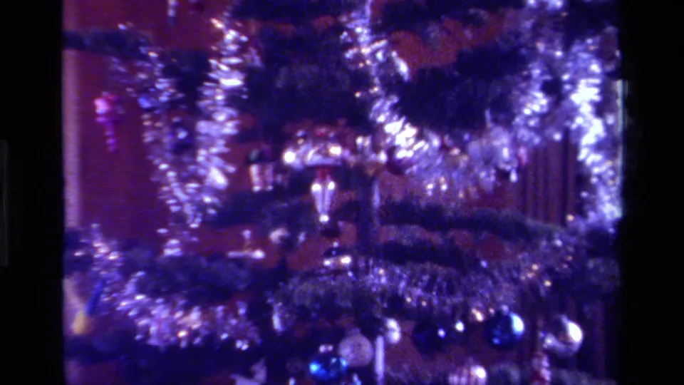 1979 California home-movie frame showing a decorated Christmas tree with silver tinsel, shiny baubles, and a purple Super 8 color cast.